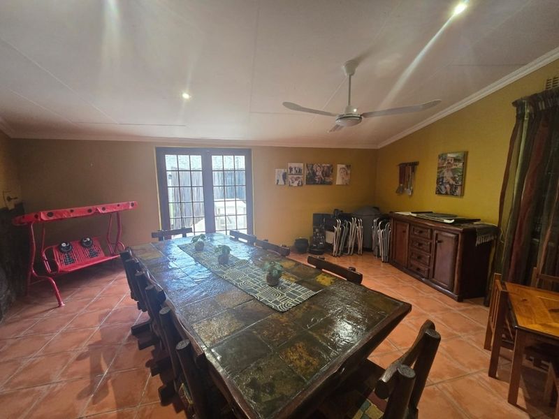 A spacious dining room featuring terracotta floor tiles, a ceiling fan, and french doors leading to the exterior.