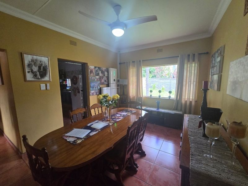 A dining room featuring tiled flooring, a ceiling fan, and cove cornicing, providing a functional space for family meals.