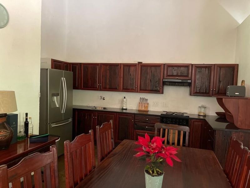 Open-plan kitchen and dining area featuring dark wood cabinetry, granite countertops, and a vaulted ceiling, providing a functional and spacious layout.