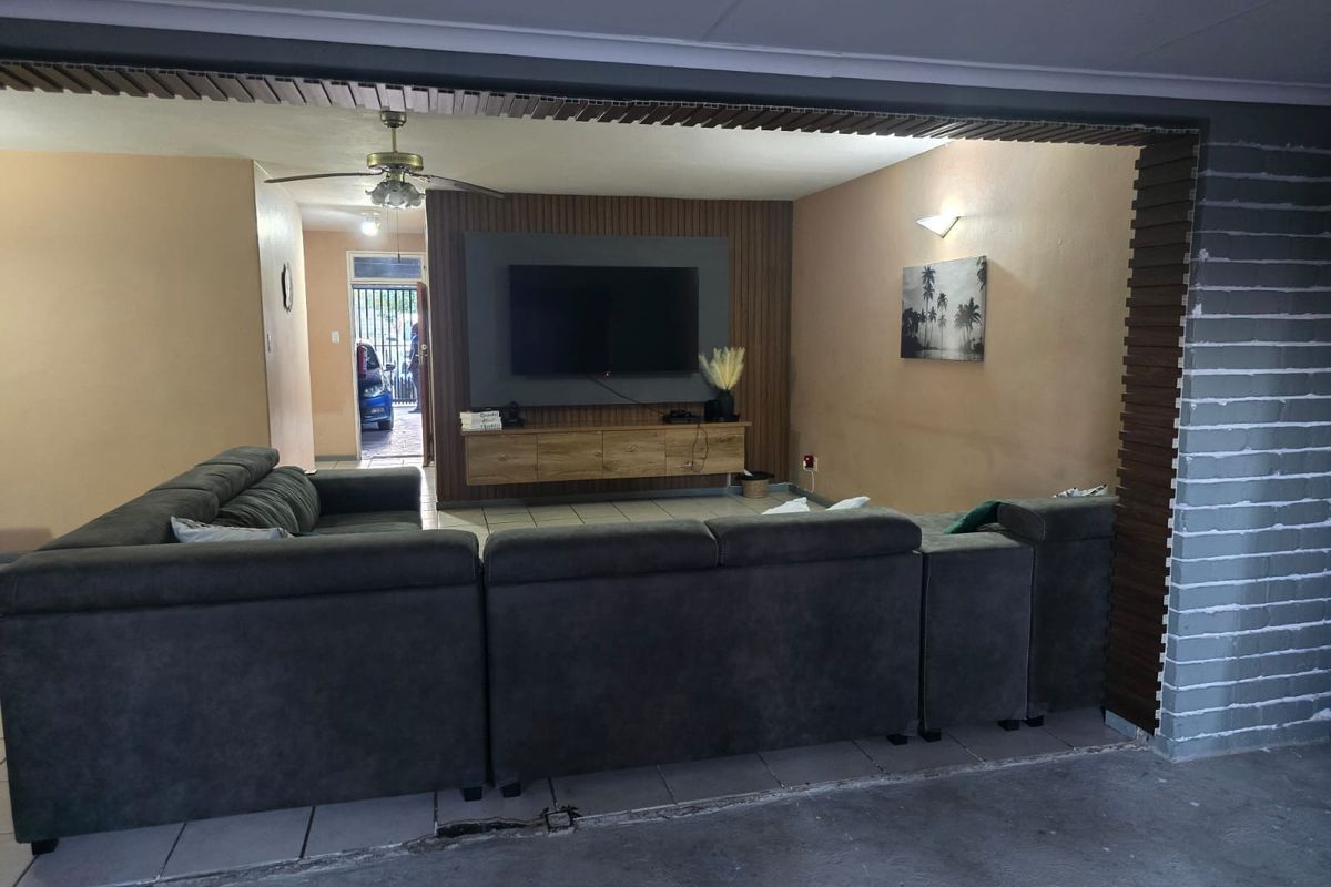 Living room featuring a slatted wood feature wall, wall-mounted media unit, ceiling fan, and tiled flooring.