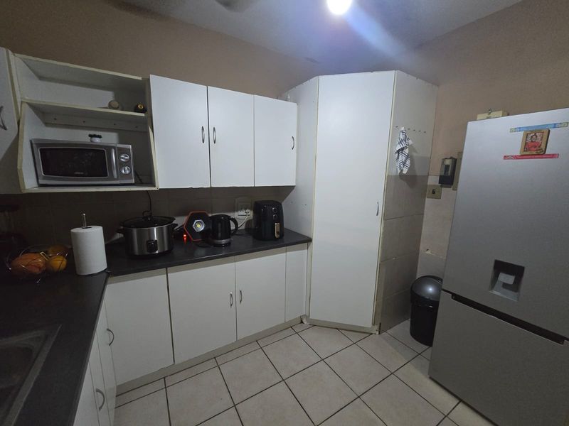 A functional kitchen featuring white built-in cabinetry, dark laminate countertops, and tiled flooring, offering practical storage and workspace.