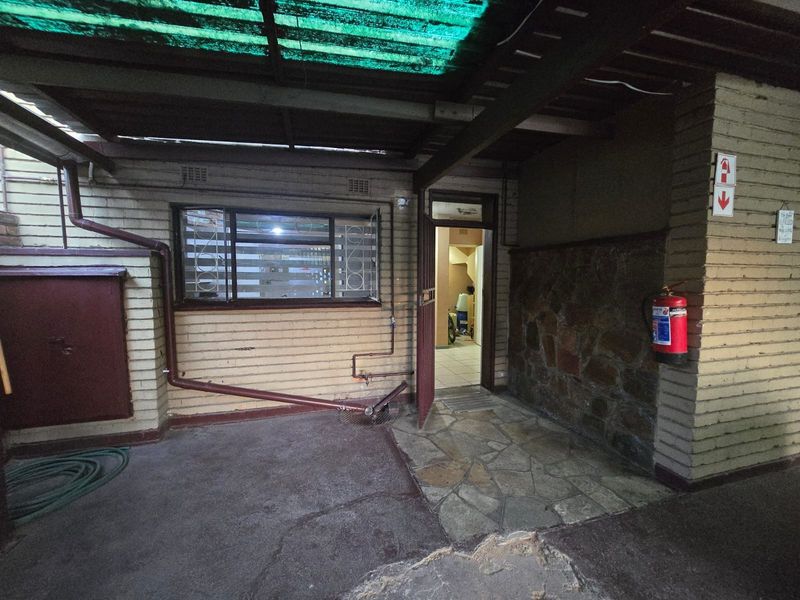 A covered outdoor patio area featuring brick and stone wall finishes, concrete flooring, and direct access to the interior of the apartment.