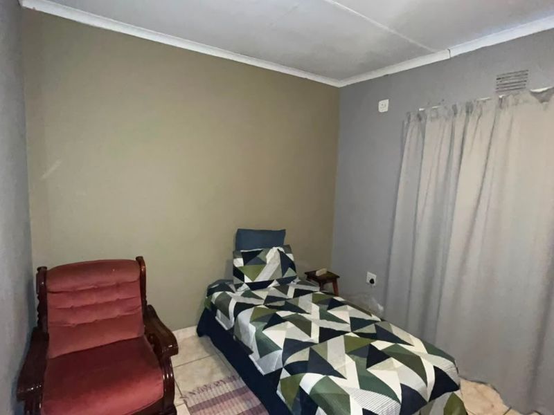 A functional bedroom featuring tiled flooring, coved ceilings, and neutral wall tones, providing a simple and practical living space.
