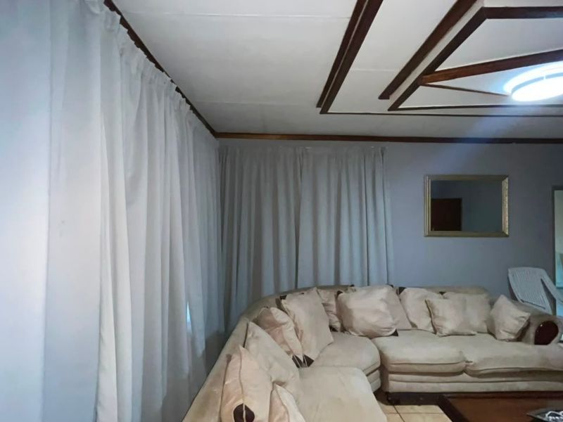 A living room featuring tiled flooring and a decorative recessed ceiling design with a central light fixture.