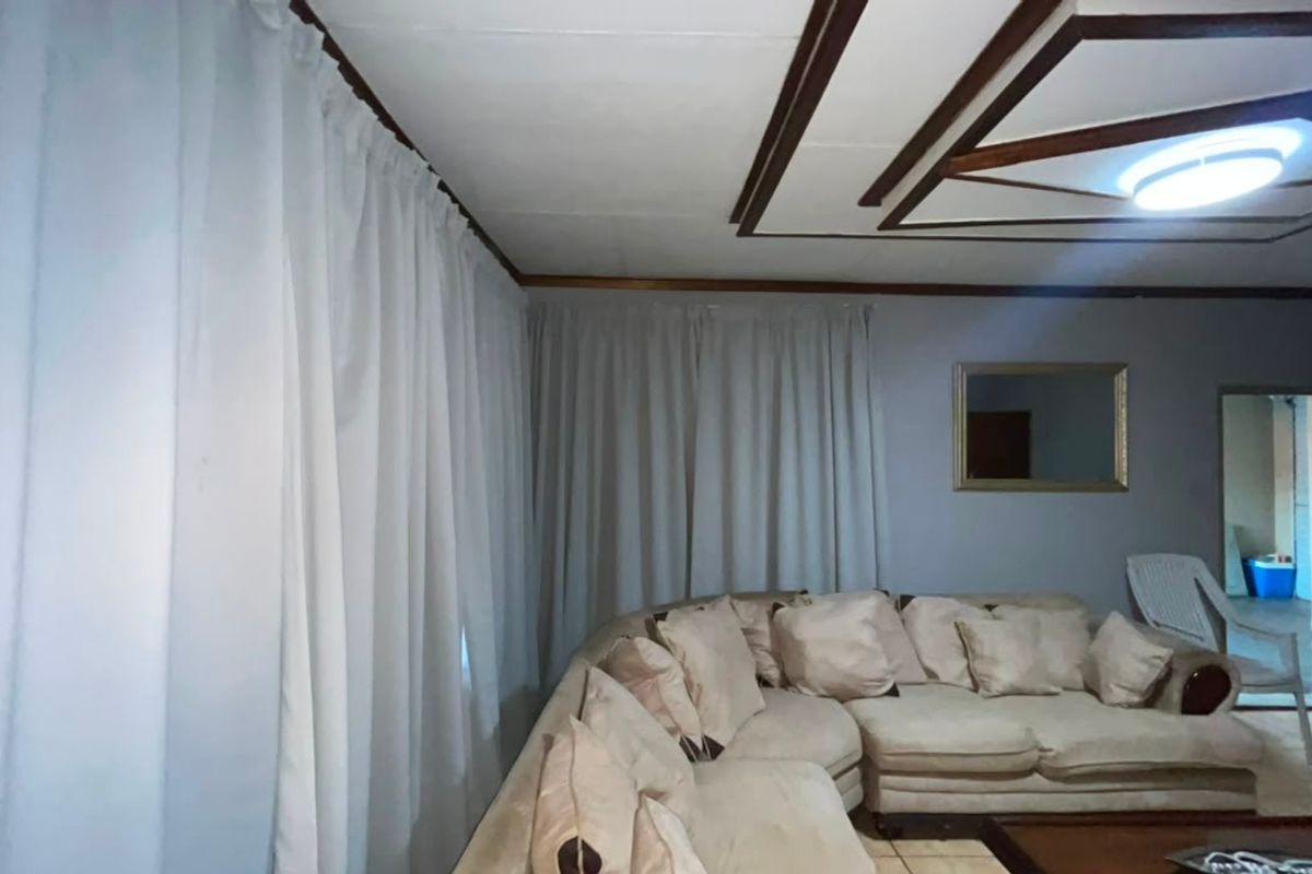 A living room featuring tiled flooring and a decorative recessed ceiling design with a central light fixture.