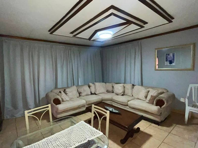 A living room featuring tiled flooring and a decorative ceiling design, providing a functional space for relaxation.