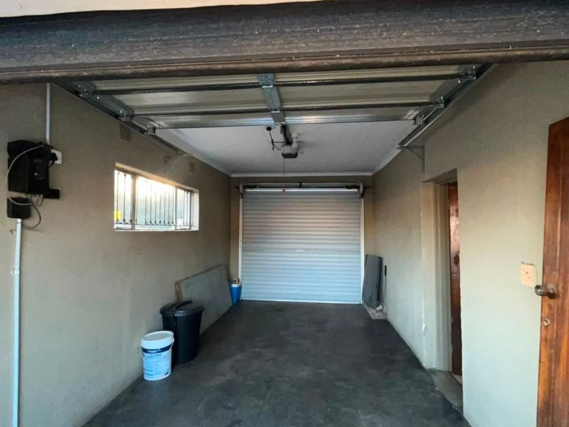 A functional single-car garage featuring concrete flooring, an automated roll-up door, and convenient internal access to the main dwelling.