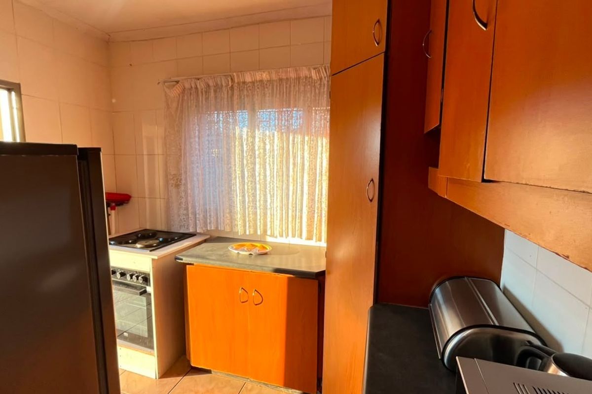 A functional kitchen featuring built-in wooden cabinetry, a built-in oven with hob, and tiled wall finishes, offering potential for modernization.