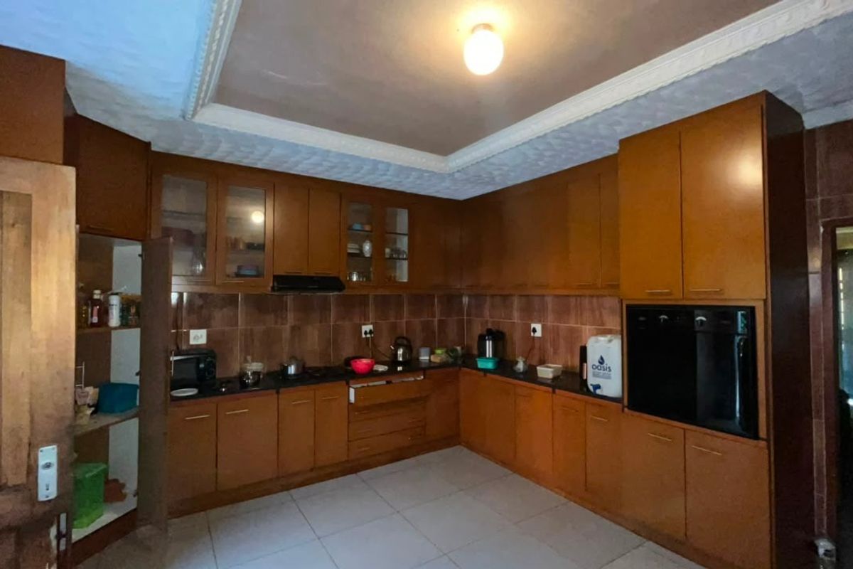 A functional kitchen featuring extensive wooden cabinetry, integrated oven, extractor fan, tiled backsplash, and tiled flooring with a coved ceiling finish.