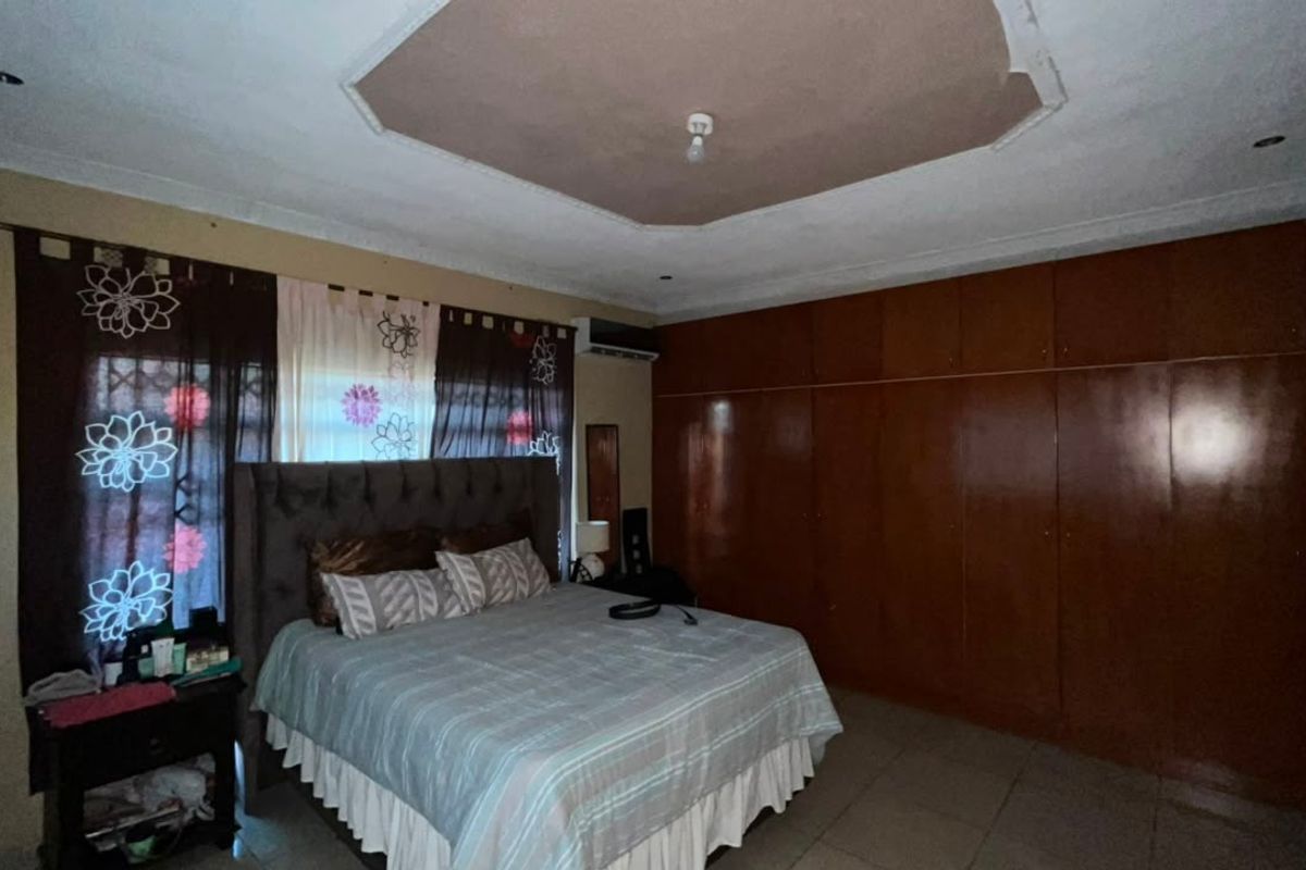 Spacious bedroom featuring extensive built-in wooden cupboards, a recessed ceiling design, and an integrated air conditioning unit.