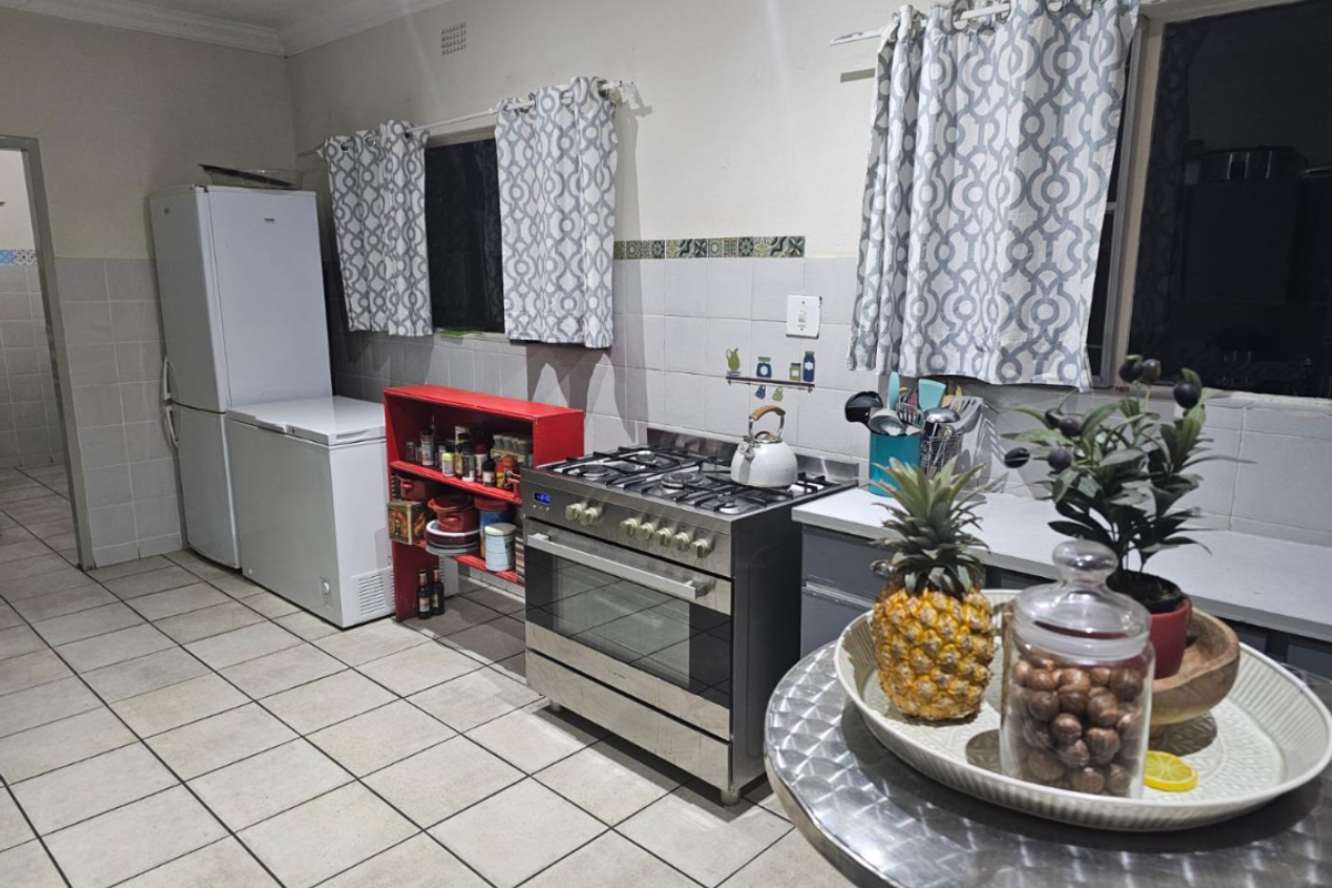 A functional kitchen featuring tiled flooring, a gas stove with oven, and tiled backsplash, offering a practical layout for daily cooking and food preparation.