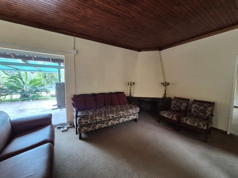 Living room featuring a timber ceiling, corner fireplace, and sliding glass door access to the outdoor patio area.