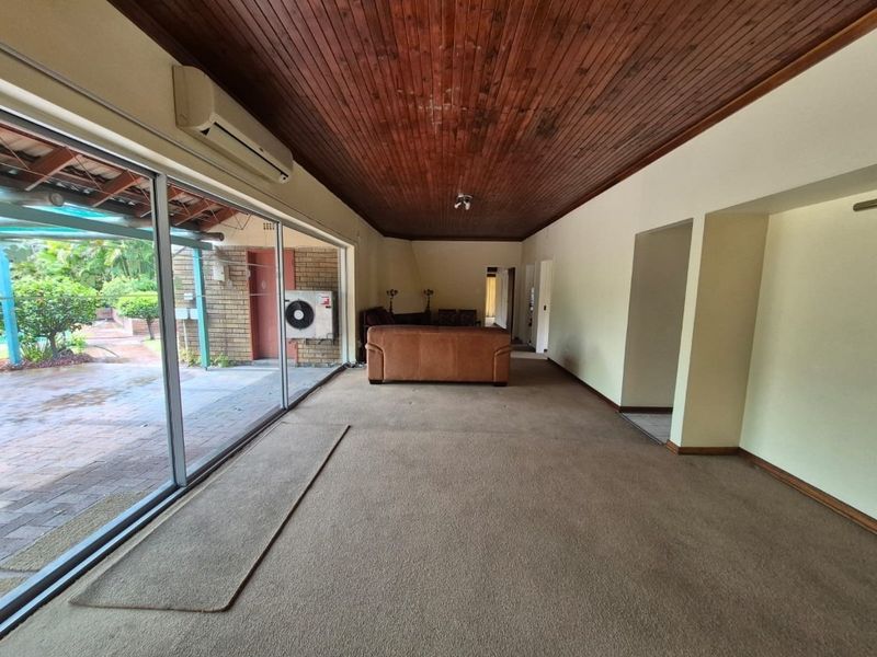 Spacious living area featuring a timber-clad ceiling, wall-mounted air conditioning, and large sliding glass doors providing direct access to the outdoor patio area.