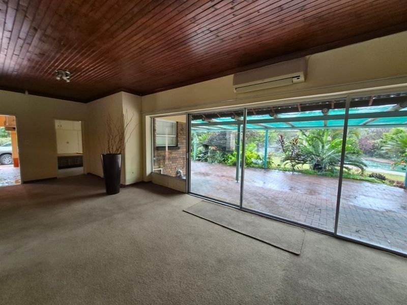 Spacious living area featuring a timber ceiling, split system air conditioning, and large sliding glass doors providing direct access to the outdoor patio area.