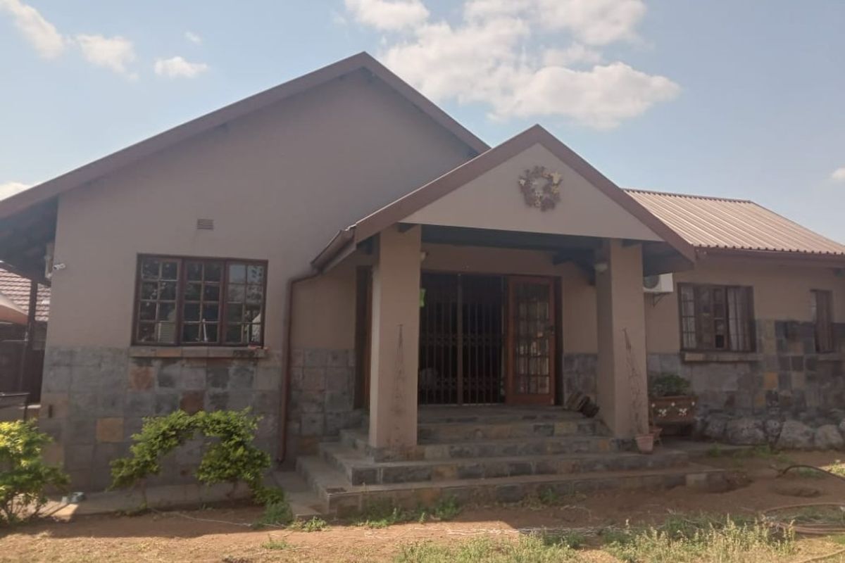 Front elevation of a single-story house featuring stone cladding, a gabled roof, and a covered entrance porch with security gate.