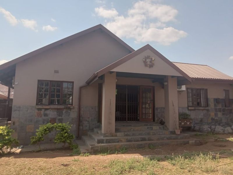 Front elevation of a single-story house featuring stone cladding, a gabled roof, and a covered entrance porch with security gate.