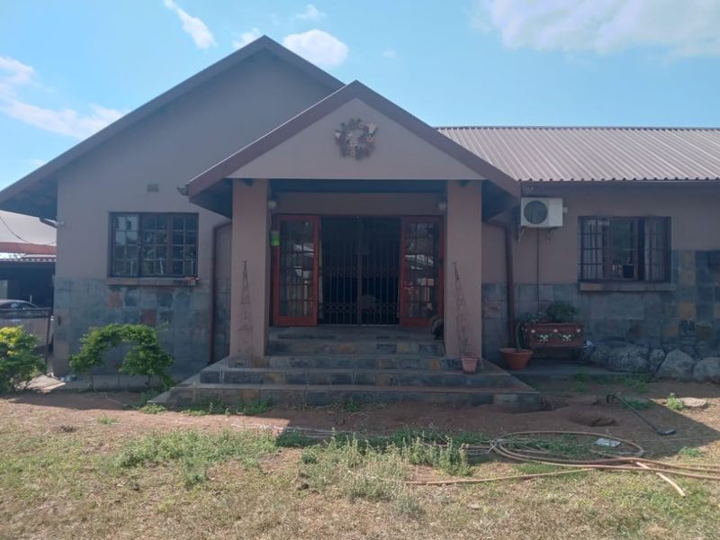 Front elevation of a single-story house featuring stone cladding, a covered entrance porch, and a metal roof.