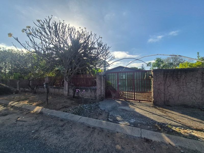 Front view of the property featuring a metal security gate, perimeter wall, and driveway access from the street.