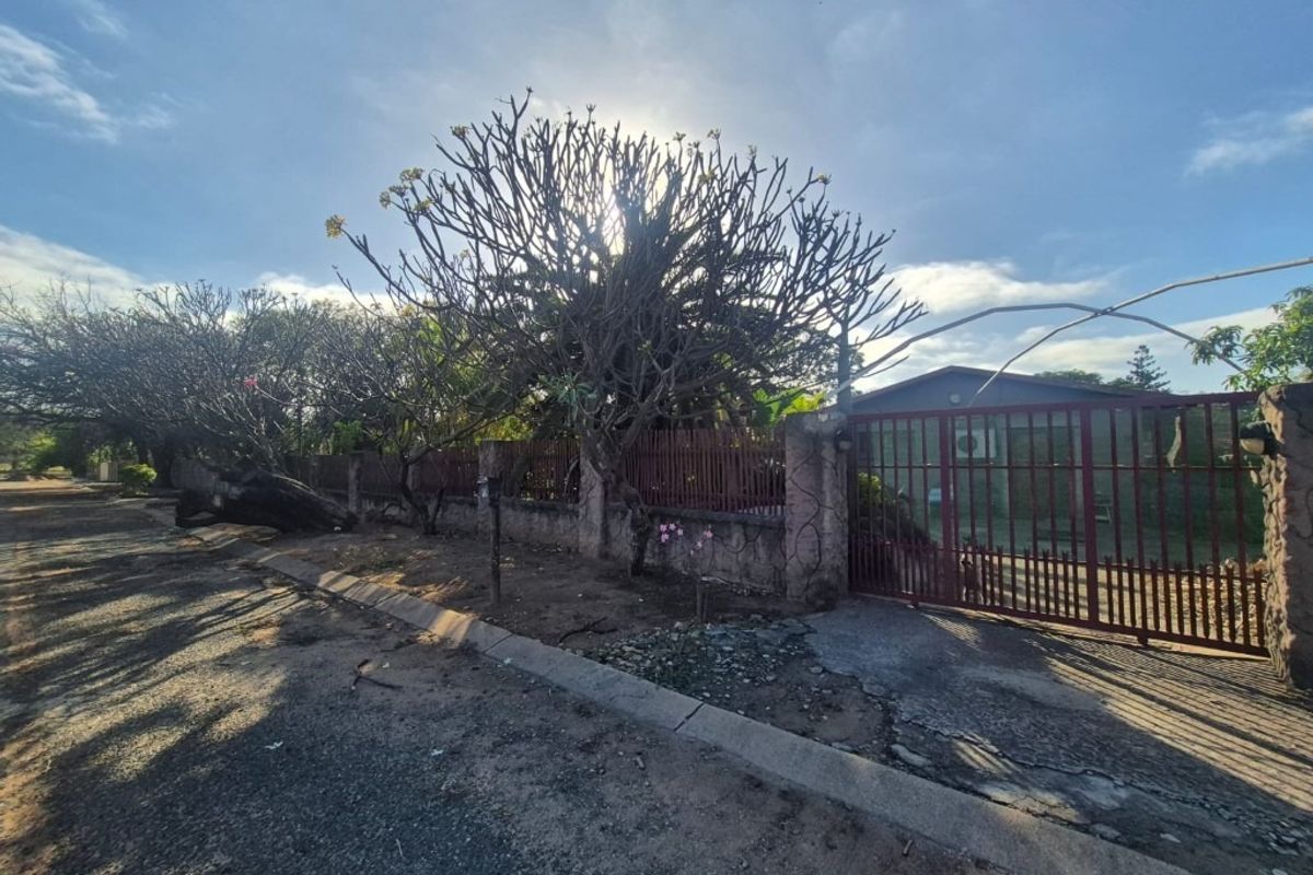 Street view of the property frontage featuring a perimeter wall, metal gate, and concrete driveway access.