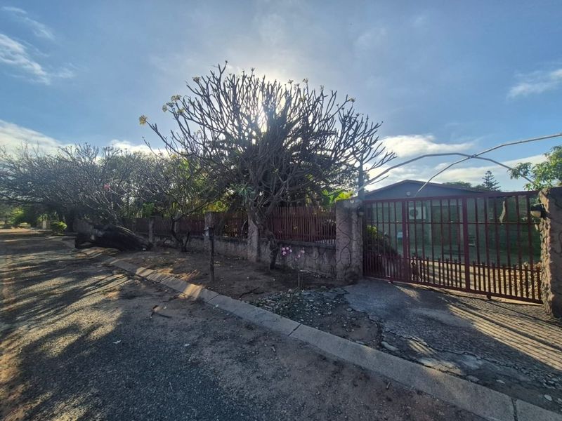 Street view of the property frontage featuring a perimeter wall, metal gate, and concrete driveway access.