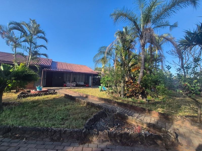 Rear view of the property featuring a covered patio, tiled roof, and a landscaped garden with paved pathways.