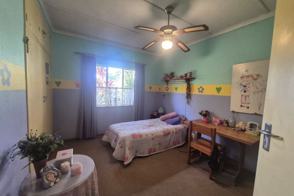 A bedroom featuring built-in cupboards, a ceiling fan, and carpeted flooring, offering a functional space with potential for modernization.