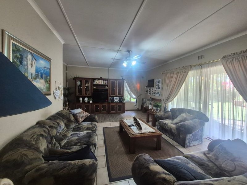 Spacious living room featuring tiled flooring, a ceiling fan, and large sliding glass doors providing natural light and garden access.