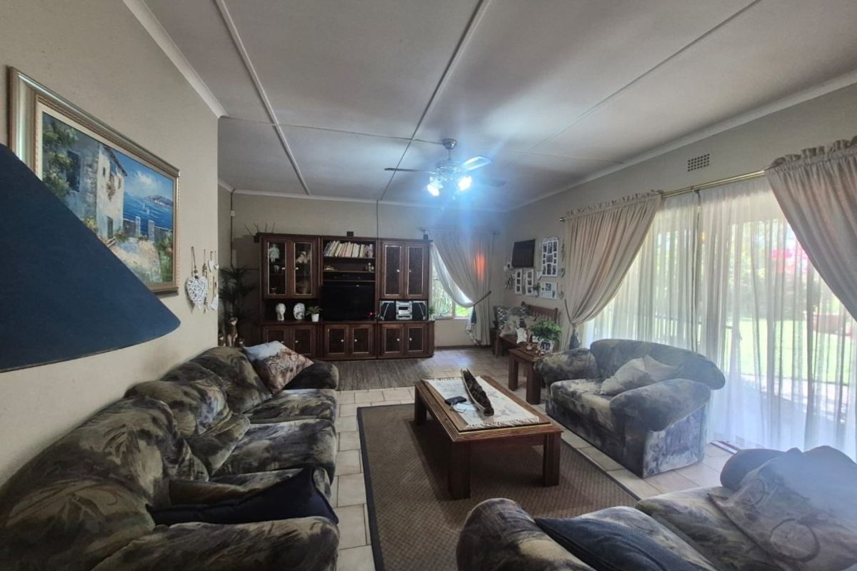 Spacious living room featuring tiled flooring, a ceiling fan, and large sliding glass doors providing natural light and garden access.