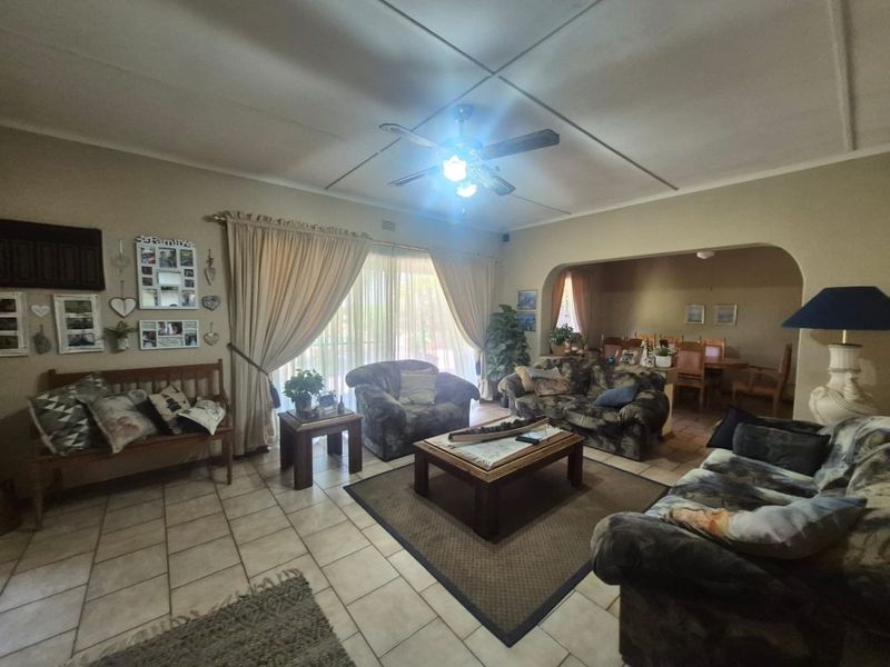 Spacious open-plan living and dining area featuring tiled flooring, a ceiling fan, and an arched transition between the two living spaces.