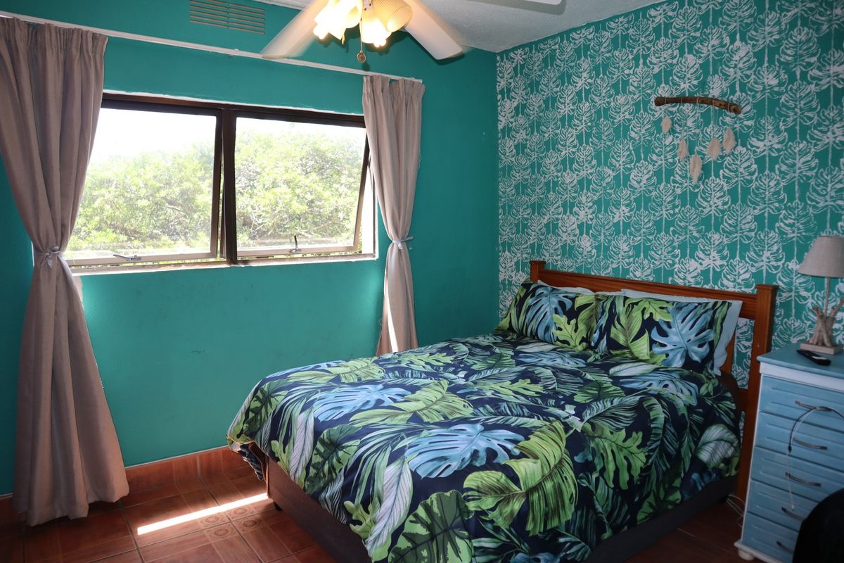 A bedroom featuring tiled flooring, a ceiling fan, and a window providing natural light.
