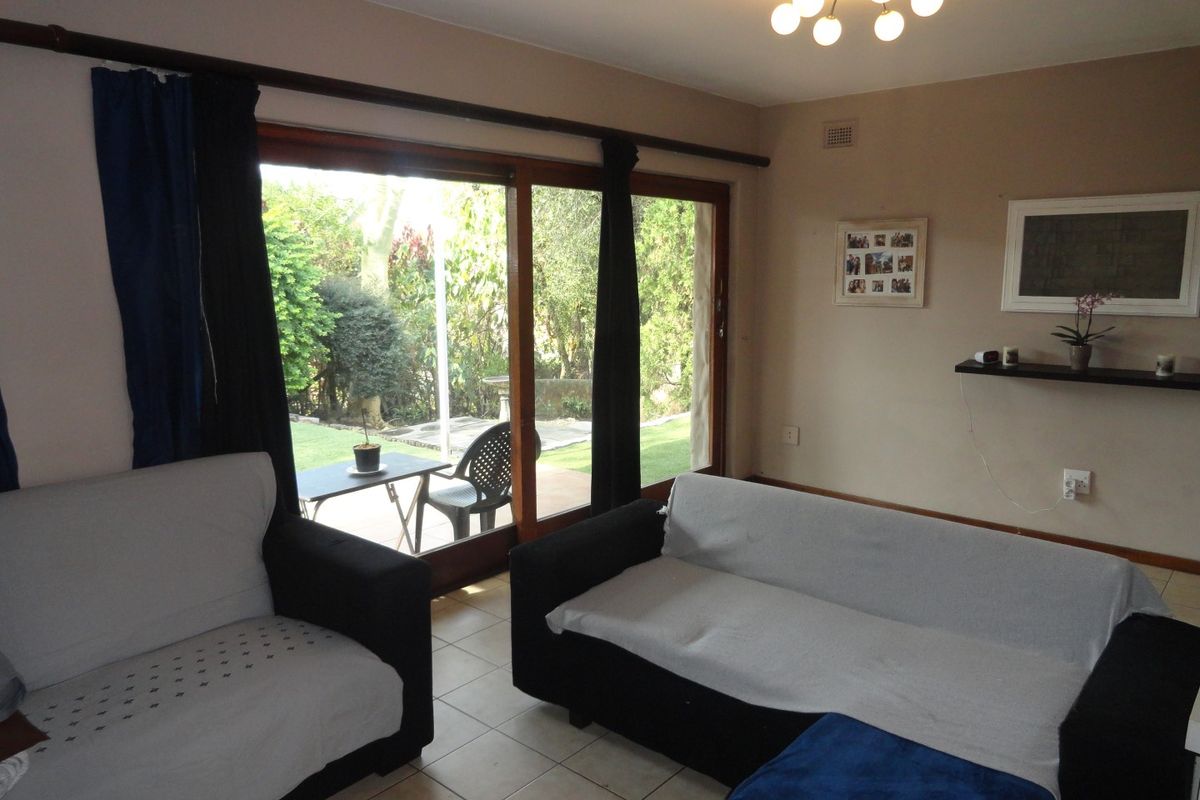 A living room featuring large sliding glass doors that provide direct access to the garden and patio area.