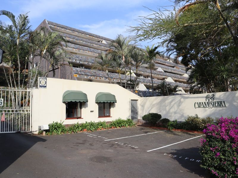 Front entrance view of Cabana Sierra apartment complex featuring a paved visitor parking area, secure gated access, and multi-level residential building.
