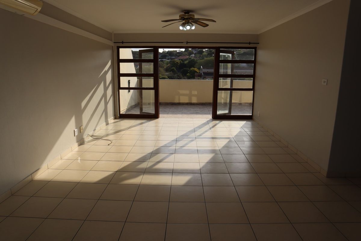 Spacious, empty living area featuring tiled flooring, a ceiling fan, air conditioning, and large timber-framed glass doors opening onto a private balcony.