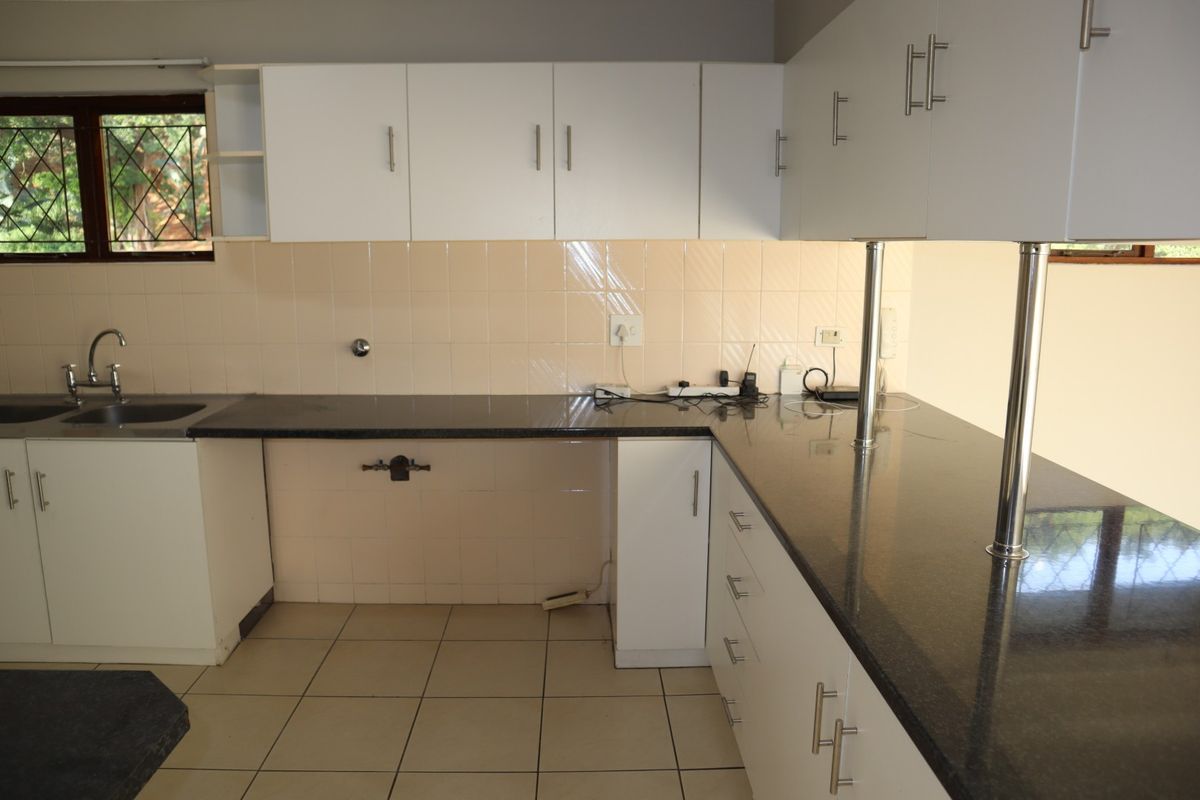 A functional kitchen featuring white cabinetry, dark granite countertops, tiled backsplash, and ceramic flooring, offering a clean and practical workspace.