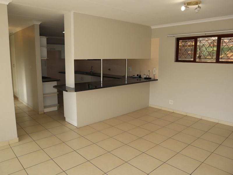 Open plan living area featuring tiled flooring and a functional kitchen with a granite breakfast counter and built-in cabinetry.