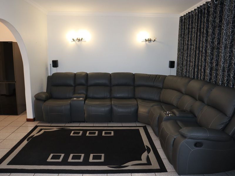 A living room featuring ceramic tiled flooring, wall-mounted lighting, and an arched entryway leading to an adjacent space.