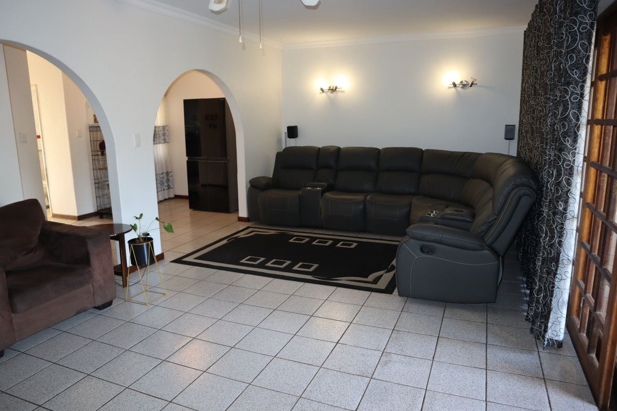 Spacious living room featuring tiled flooring, decorative archways leading to adjacent areas, and a sliding glass door providing access to the exterior.