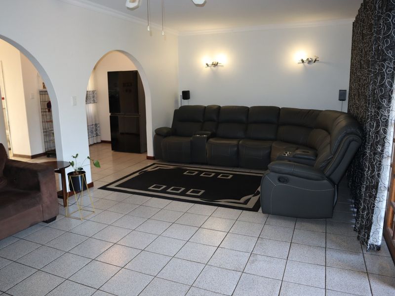 Spacious living room featuring tiled flooring, decorative archways leading to adjacent areas, and a sliding glass door providing access to the exterior.