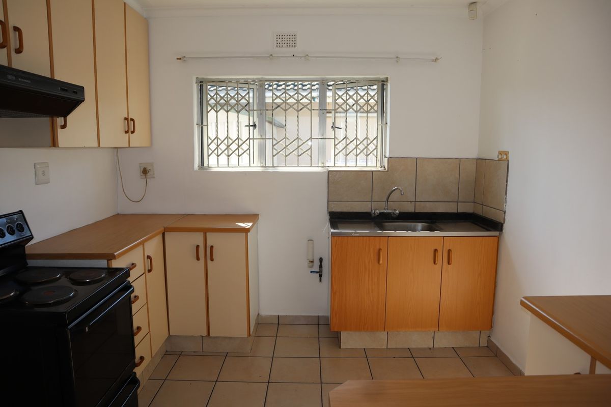 A functional kitchen featuring laminate countertops, built-in cabinetry, a stainless steel sink, and tiled flooring, offering a practical layout for renovation.