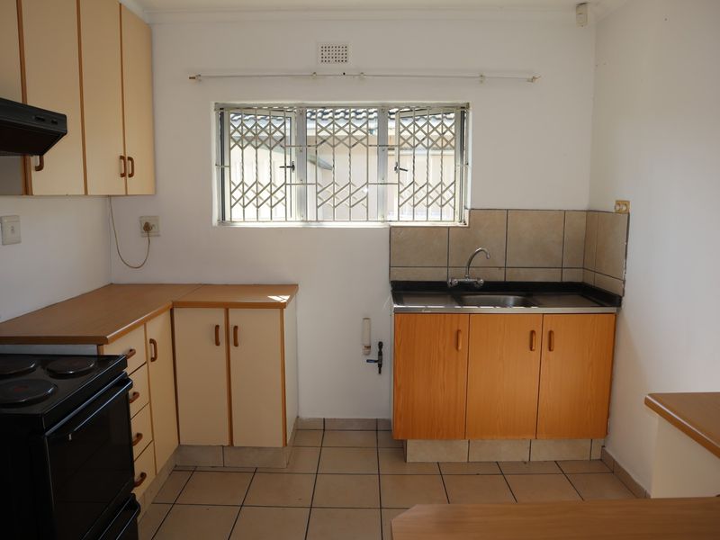 A functional kitchen featuring laminate countertops, built-in cabinetry, a stainless steel sink, and tiled flooring, offering a practical layout for renovation.
