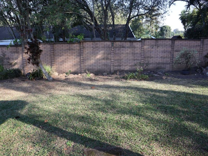 A private rear garden area featuring a established lawn and a solid brick boundary wall.
