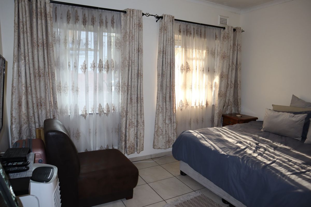 A bedroom featuring tiled flooring and dual windows with curtain rods, providing natural light.