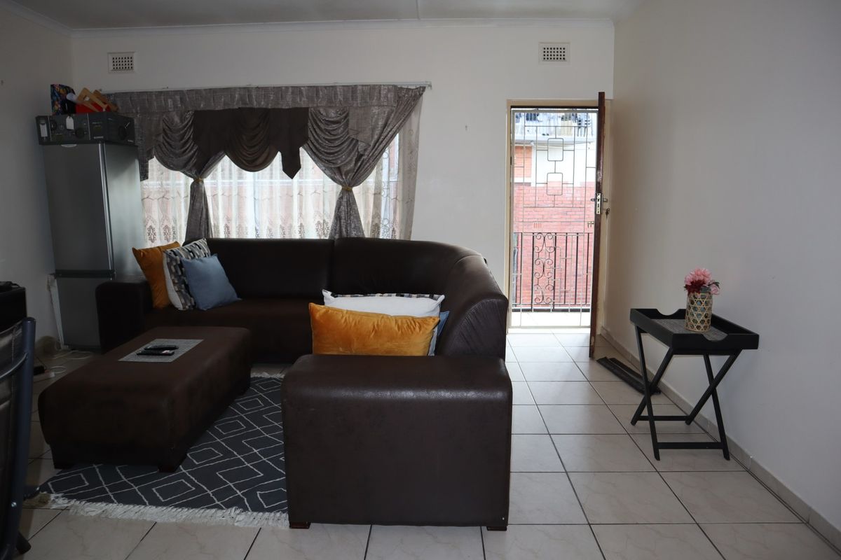 A living room featuring tiled flooring and direct access to an external balcony through a security gate.