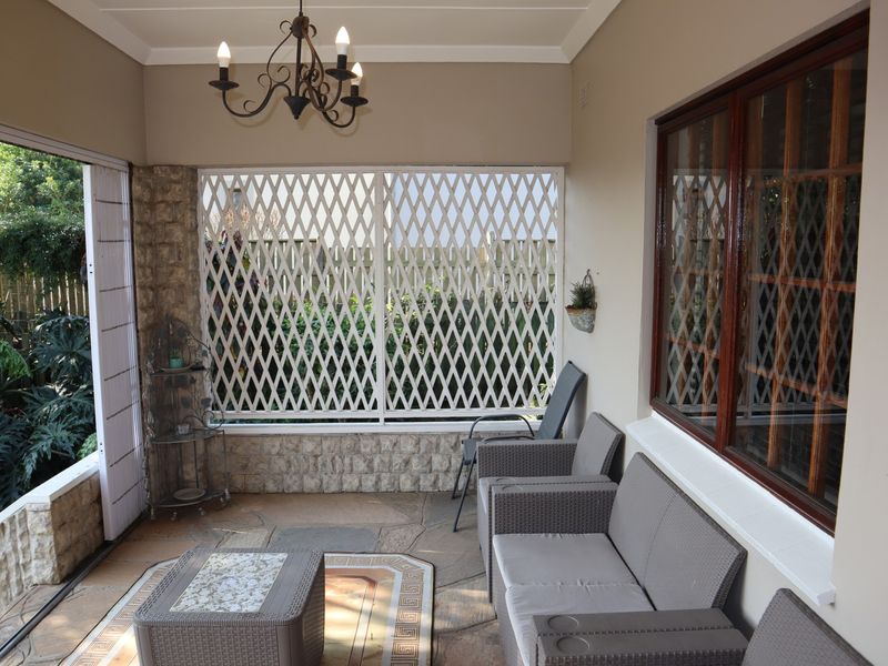 A covered patio area featuring flagstone flooring, stone-clad accents, and secure metal screening, providing a comfortable transition to the garden.