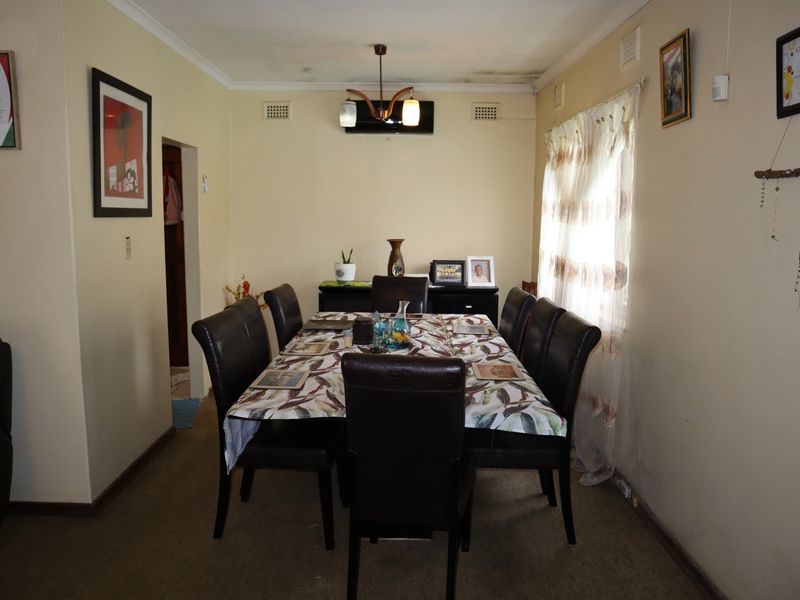 Dining room featuring a ceiling light fixture, air conditioning unit, and ventilation grilles, showing signs of ceiling water damage and worn carpeting.