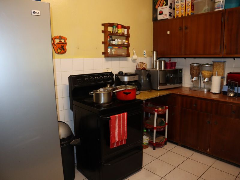 A functional kitchen featuring traditional wooden cabinetry, a tiled backsplash, and tiled flooring, providing a practical workspace with essential built-in storage.
