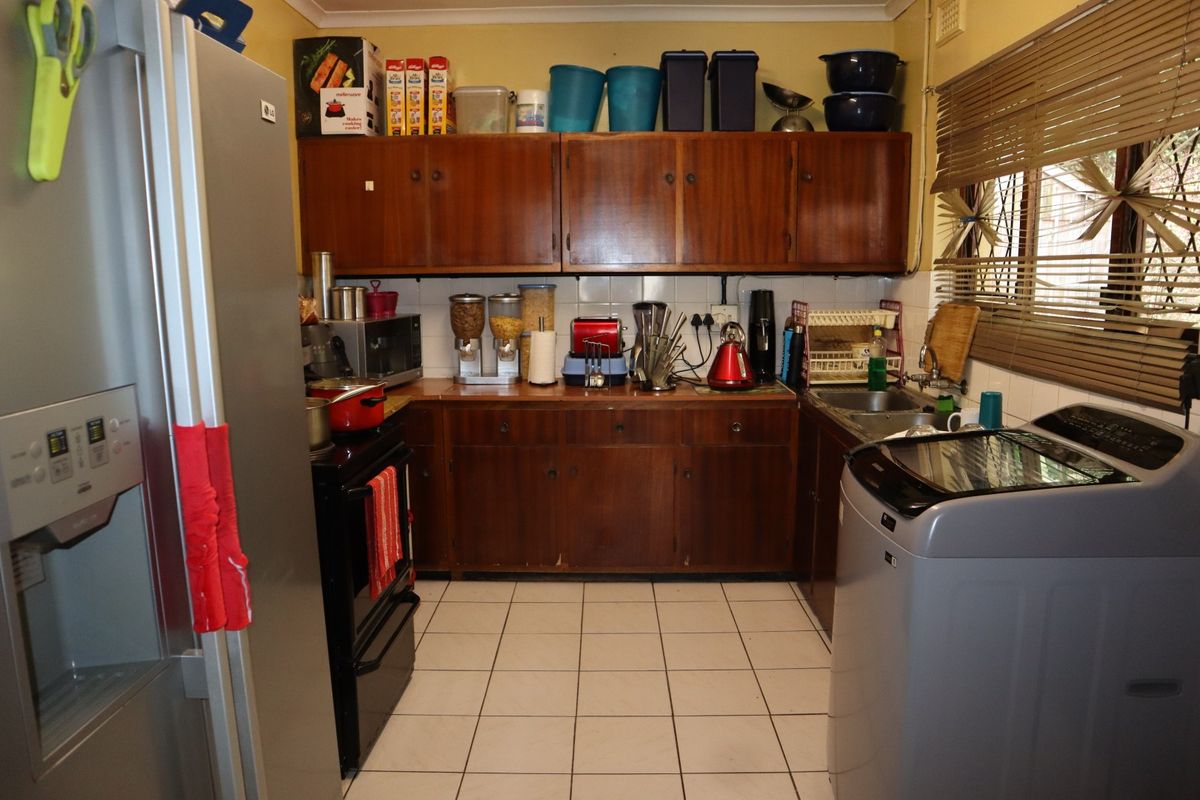 A functional kitchen featuring wooden cabinetry, tiled flooring, and a tiled backsplash, providing a practical layout for daily meal preparation.