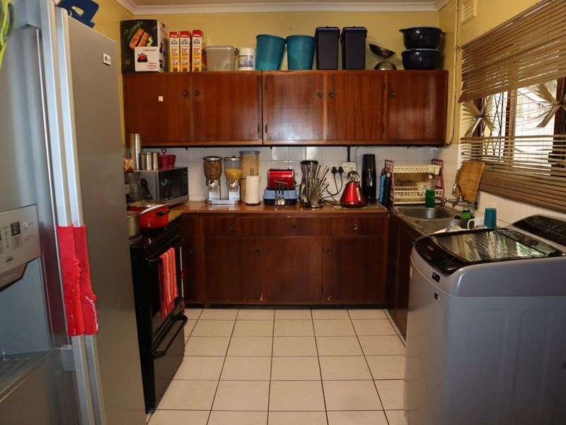 A functional kitchen featuring wooden cabinetry, tiled flooring, and a tiled backsplash, providing a practical layout for daily meal preparation.