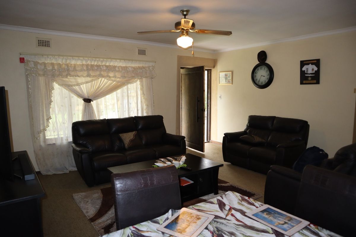 A living room featuring a ceiling fan and carpeted flooring, offering a functional space with potential for cosmetic updates to modernize the interior.