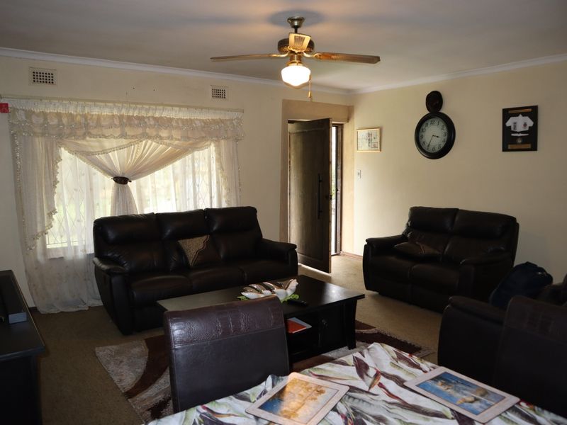 A living room featuring a ceiling fan and carpeted flooring, offering a functional space with potential for cosmetic updates to modernize the interior.